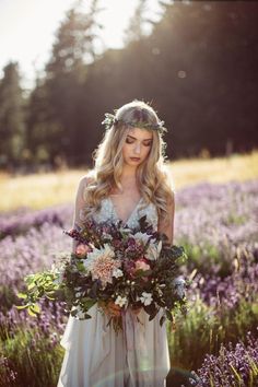 a woman standing in a field holding a bouquet