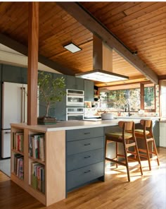 a kitchen with wooden floors and an island in the middle, surrounded by bookshelves