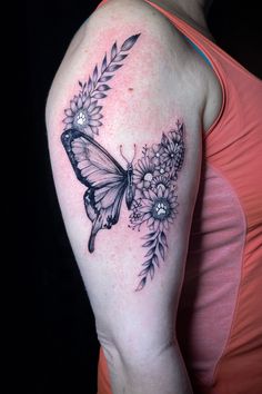 a woman's arm with a butterfly and flowers tattoo on the left side of her shoulder