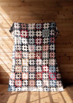 an old quilt is sitting on the floor in front of a wood paneled wall