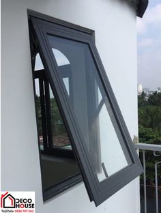 an open window on the side of a white building with trees in the back ground