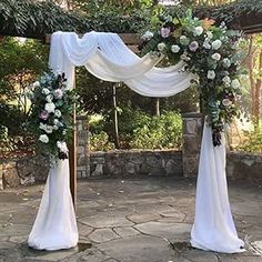 an outdoor wedding setup with white drapes and flowers