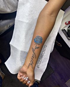 a woman's arm with a blue rose tattooed on the left side of her arm