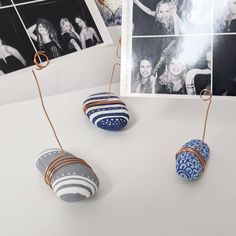 three small balls are hanging from wire on a white table with black and white photos in the background