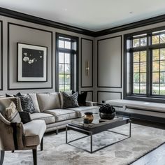 a living room with couches, tables and two large windows in the wall behind them