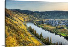 a river running through a lush green hillside next to a town on top of a hill