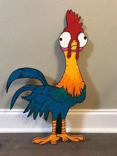 a paper cut out of a rooster standing on the floor next to a gray wall