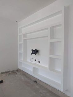 an empty room with white shelves and electrical wires on the wall in front of it