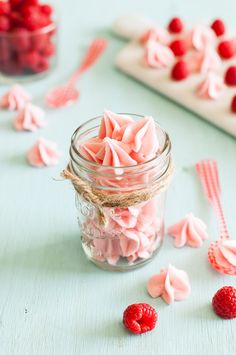 a mason jar filled with raspberries and marshmallows on top of a table