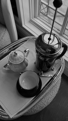 a tray with a tea pot and two cups sitting on it next to a window