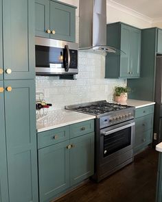 a kitchen with green cabinets and stainless steel stove top oven in the middle of it