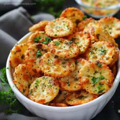 a white bowl filled with cheesy crackers and parsley