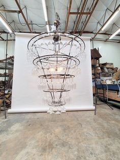 a chandelier hanging from the ceiling in front of a large white wall with lots of glass beads