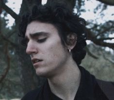 a close up of a person wearing a black shirt and looking at his cell phone