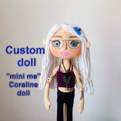 a doll with white hair and blue eyes is standing on a wooden stick in front of a sign that says custom doll