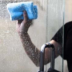 a person holding a blue towel in front of a window with water droplets on it