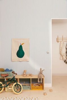 a toy bike sitting next to a wooden table in a child's room with striped walls