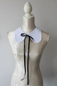 Collar necklace in white color with black ties. Round shape. Black ribbon tied on the front. Plain white on the other side. Collar gives a chic touch to simple dresses and blouses. One size. Handmade item. Wonderful gift for women or female friends. White Bow Jewelry For Formal Occasions, White Formal Jewelry With Bow Detail, White Ribbon Jewelry For Party, Formal White Jewelry With Bow Detail, Elegant White Jewelry With Ribbon, White Ribbon Necklace For Parties, Formal White Bow Jewelry, Elegant White Ribbon Necklaces, Elegant Black Choker With Black Ribbon