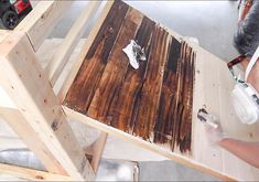 a man is painting a wooden table with white paint and brown stain on the top