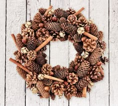 a wreath made out of pine cones and cinnamons on top of a white wooden surface