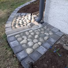 a brick walkway with rocks and gravel in the middle next to a house on a sunny day