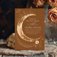 a wedding card with the moon and stars on it, next to some orange roses