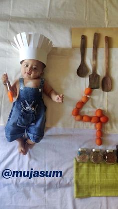 a baby wearing a chef's hat and overalls next to various kitchen utensils