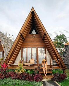 there is a woman sitting on the steps in front of a wooden house with flowers