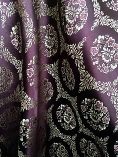 a purple and white fabric with floral designs on the top, as well as an intricate design