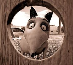 a close up of a cartoon character looking through a hole in a wooden door frame