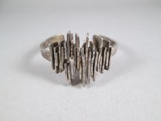 A modernist brutalist silver cuff bracelet, possibly by Danish jewelry maker Poul E. Boesen. I could find very little of Boesen's work online, only a brooch marked P.E.B.  This wondrous piece most likely dates from the 1960s, is stamped 830s and scratch tests as silver weighing 74.7 grams.  The cuff features jagged brutalist panels vertically wedged and soldered together for dramatic effect, with a tapered band.  I haven't polished it and will leave that decision to the new owner.  It will make a fine addition to any serious mid-century modernist jewelry collection. Inner circumference 7".  Width of panels 1 3/8" Danish Jewelry, Chunky Silver Bracelet, Silver Wrap Bracelet, Modernist Jewelry, Jewelry Ads, Work Online, Silver Cuff Bracelet, Jewelry Maker, Metal Bracelets