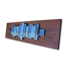 a wooden wall hanging with blue squares and strings attached to the wood, on a white background