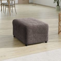 a living room with wooden floors and a brown footstool on top of a hard wood floor