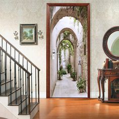 an open door leading to a hallway with potted plants on the wall and stairs