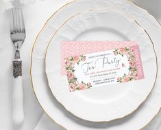 a white plate with a pink and gold place card on it next to silverware