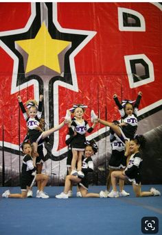 a group of cheerleaders performing in front of a large red and yellow sign