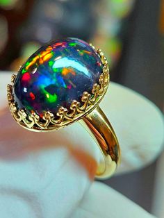 Black fire opal, this one is a beauty and was a challenge to photographed well. Very colorful and bright with a lovely horizontal honeycomb pattern. stone is 12x16mm and 8.9cts.  Mounted in a 14k solid gold heavy crown style bezel ring. The prongs will be closed when the ring size is determined. Black Opal Jewelry Opal Auctions, Opal And Black Diamond Ring, Black Opal Ring Opal Auctions, Black Cabochon Opal Ring, Elegant Multicolor Cabochon Opal Ring, Multicolor Opal Round Ring, Multicolor Opal Gemstone Ring, Multicolor Opal Ring, Fire Opal Ring Engagement