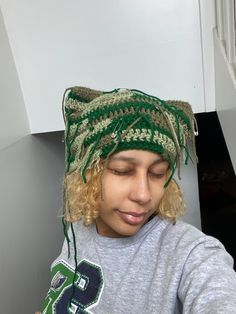 a woman with blonde hair wearing a green knitted headband and looking down at her cell phone