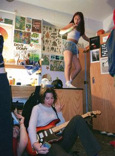 a woman standing on top of a bed next to a man with a guitar in his hand