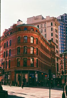 an old red brick building on the corner of a street in front of tall buildings