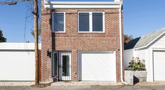 a two story brick house with white garage doors