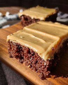 two pieces of cake sitting on top of a wooden cutting board with frosted icing