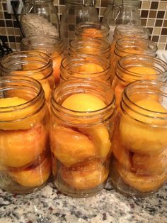 jars filled with peaches sitting on top of a counter next to a marble counter