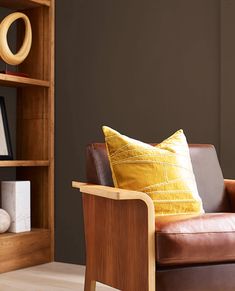 a brown leather chair sitting in front of a wooden book shelf with books on it