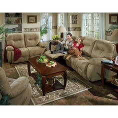 a man and two children sitting on a couch in a living room with large windows