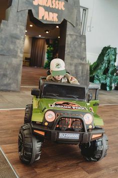 a young boy riding on top of a green toy truck