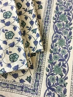 three pieces of blue and white fabric with floral designs on the edges, sitting next to each other