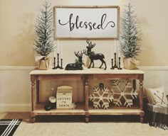 a wooden table topped with christmas decorations and deer figurines next to a sign that reads, blessed