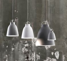 three gray and white lights hanging from the ceiling in front of a concrete wall with peeling paint