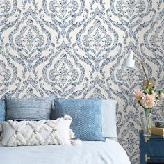 a blue and white bedroom with an intricate wallpaper pattern on the wall behind it